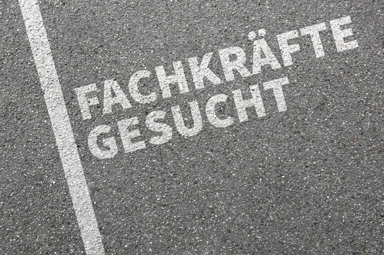 Die weiße Schrift auf dem Asphalt lautet "FACHKRÄFTE GESUCHT" - ein klarer Aufruf inmitten des Fachkräftemangels. Eine weiße Linie verläuft vertikal an der linken Seite des Bildes entlang. IFF Institut für Fach- und Führungskräfte
